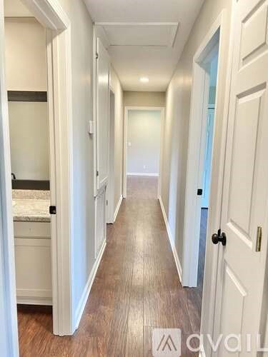 A hallway with white doors and wood flooring.