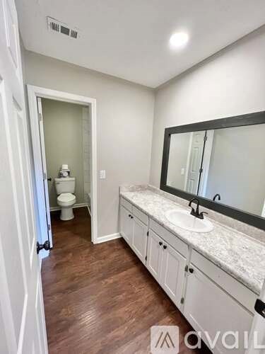 A bathroom with a toilet, sink, and mirror.