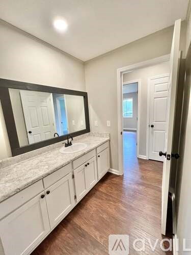 A bathroom with a marble countertop and white cabinets.