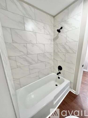A white bathtub in a bathroom with marble tiles.