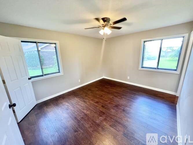 A room with a ceiling fan and two windows.