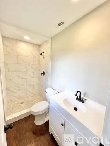 A white bathroom with a toilet, sink and shower.