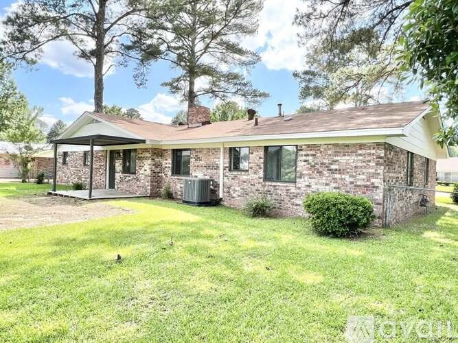 A house with a green lawn and trees in the background.