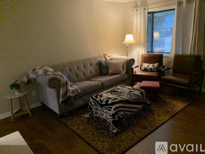 A spacious living room with hardwood floors and a kitchen area in the background.