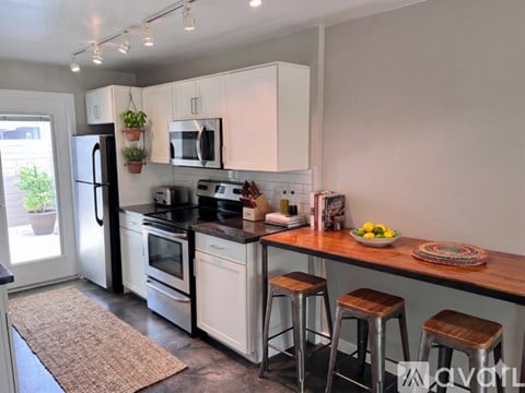 A kitchen with white cabinets and a black countertop.