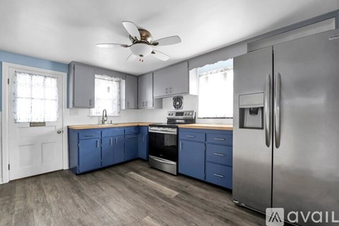 A kitchen with blue cabinets and a stainless steel refrigerator.