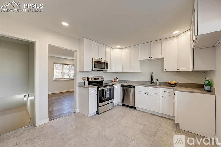 A kitchen with white cabinets and appliances is available for rent.