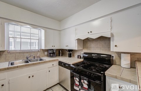A kitchen with a black stove top oven and white cabinets.