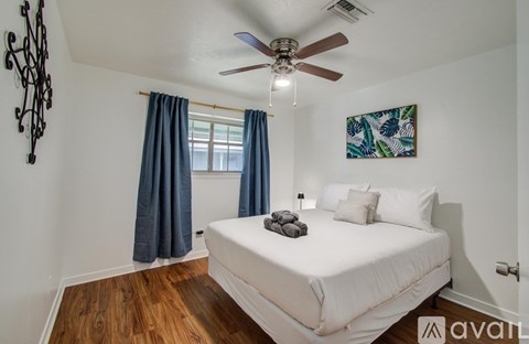 A bedroom with a white bed and a ceiling fan.