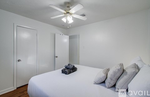 A bedroom with a bed, pillows, and a ceiling fan.