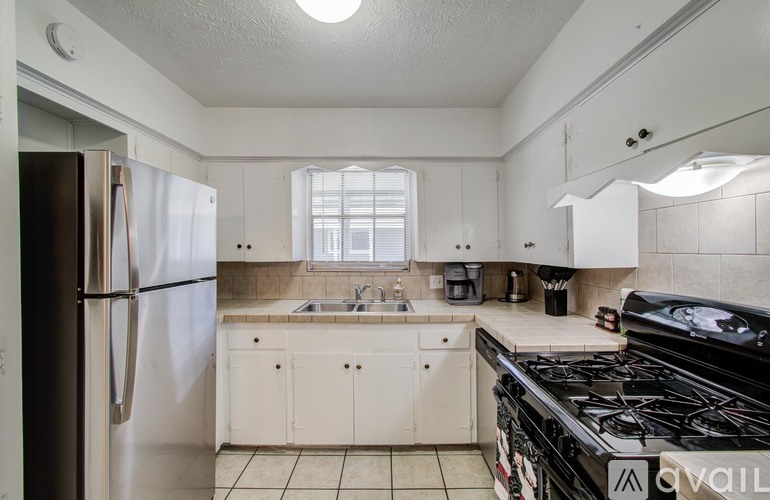 A kitchen with a black stove top oven and white cabinets.