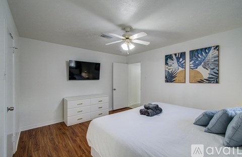 A bedroom with a bed, dresser, and ceiling fan.