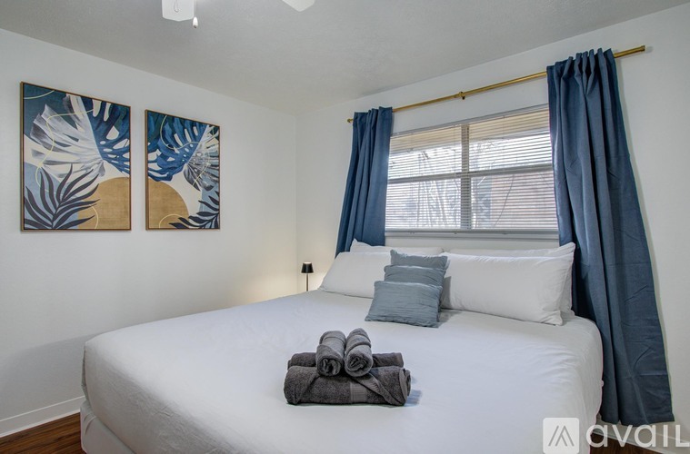A bedroom with a white bed and blue curtains.