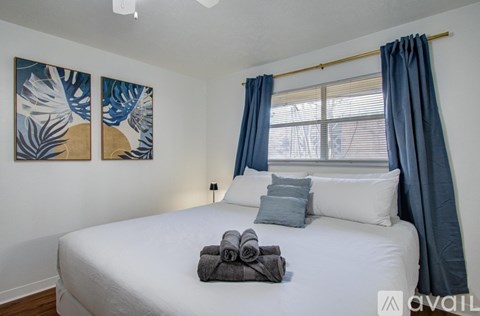 A bedroom with a white bed and blue curtains.