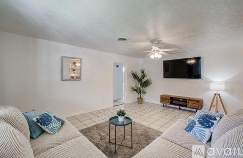A living room with a couch, a coffee table, and a flat screen TV mounted on the wall.