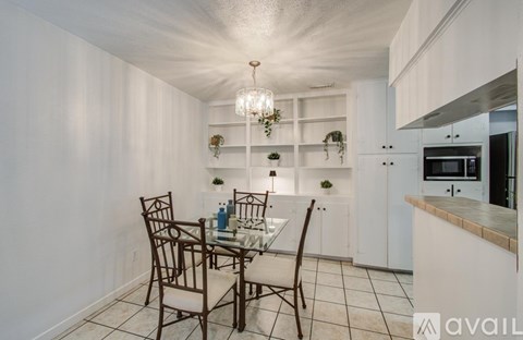 A dining room with a table set for two and a chandelier hanging from the ceiling.