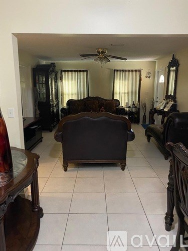 A living room with a brown couch and a ceiling fan.