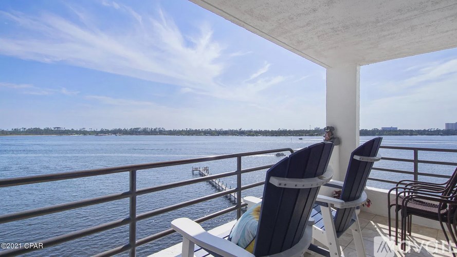Two chairs are on a balcony overlooking a body of water.