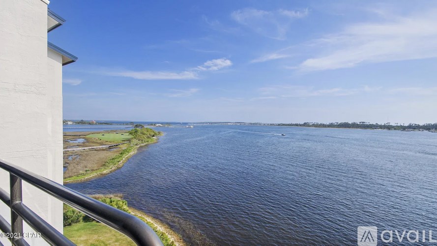 A view from a balcony overlooking a calm river with a boat in the distance.