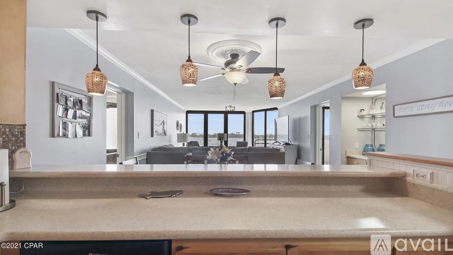 A kitchen with a large island in the middle and pendant lights hanging above.