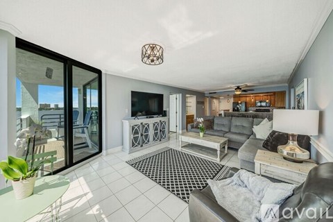 A living room with a grey couch and a black and white checkered rug.