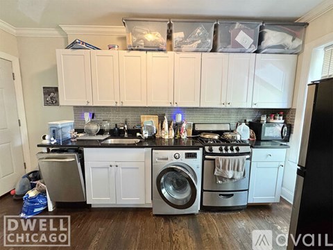A kitchen with white cabinets and black countertops is shown.