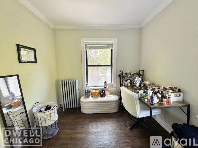 A room with a table full of makeup and a window with a white chair.