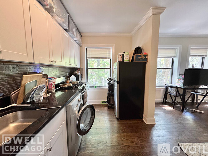 A kitchen with a black refrigerator and white cabinets.