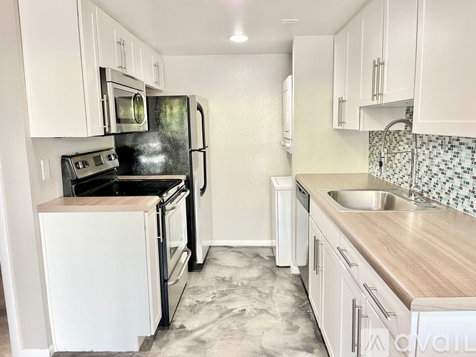 A kitchen with white cabinets and a black refrigerator.
