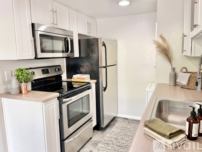 A kitchen with a black refrigerator, white cabinets, and a wooden counter.