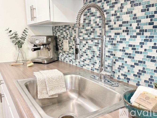 A kitchen with a stainless steel dishwasher and a white trash can.