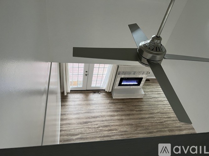A ceiling fan is mounted in a room with a wood floor and a window.
