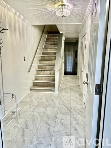 A hallway with a staircase and a chandelier.