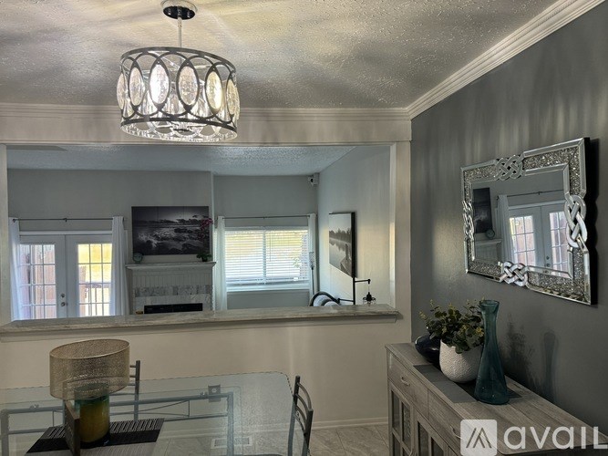 A modern kitchen with a glass table and a chandelier hanging from the ceiling.