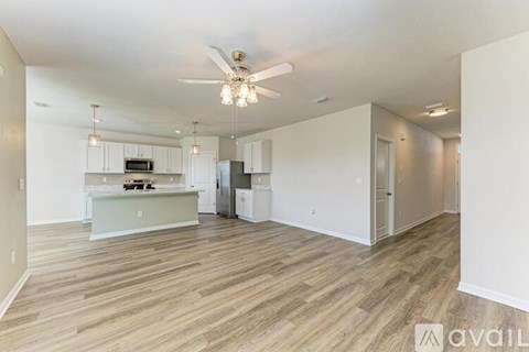 A spacious kitchen with white cabinets and a wooden floor.