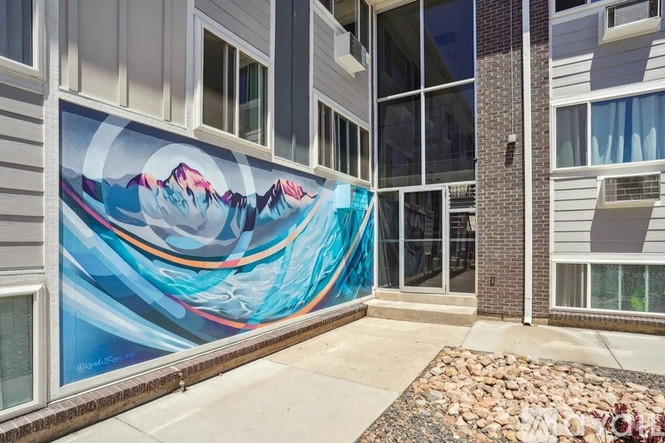 A mural of a mountain range is painted on the side of a building.