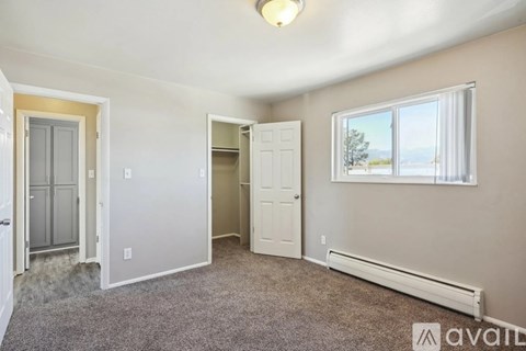 A room with a carpeted floor, a window, and a door.