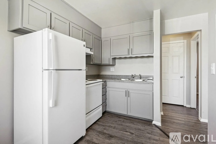 A white refrigerator is in a kitchen with white cabinets.