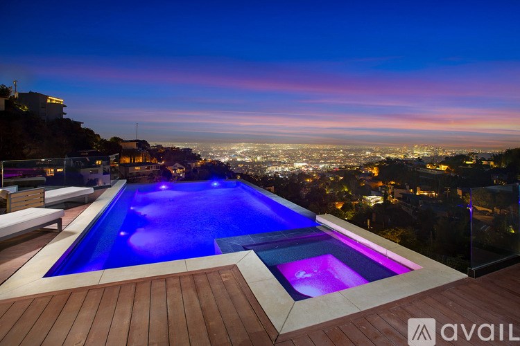 A swimming pool with a view of the city at night.