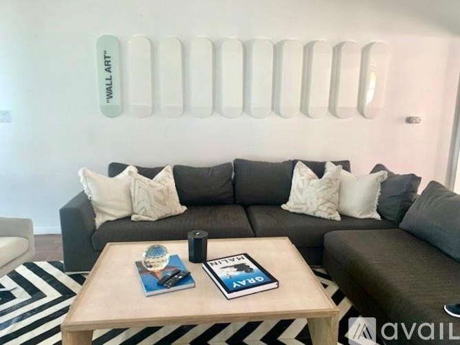 A living room with a grey couch, a coffee table, and a striped rug.