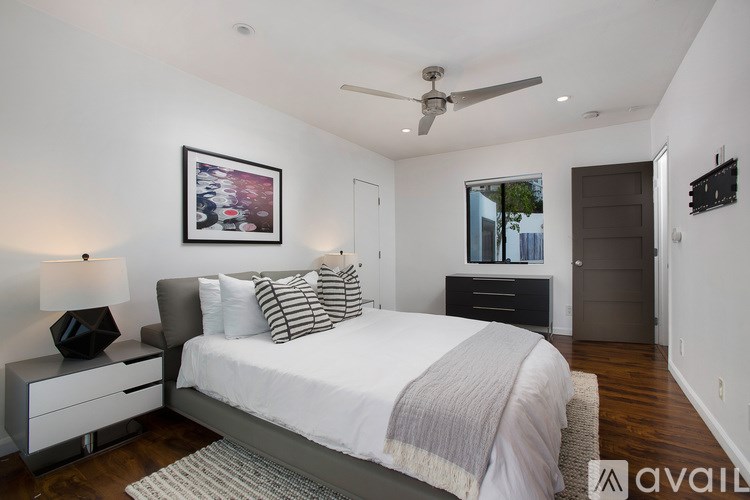 A bedroom with a bed, nightstand, and a ceiling fan.