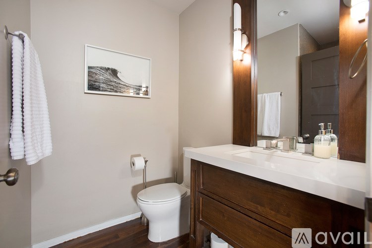 A bathroom with a toilet, a mirror, and a picture on the wall.