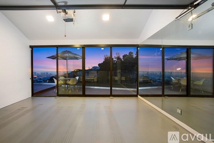 A room with a view of the city at dusk through large windows.