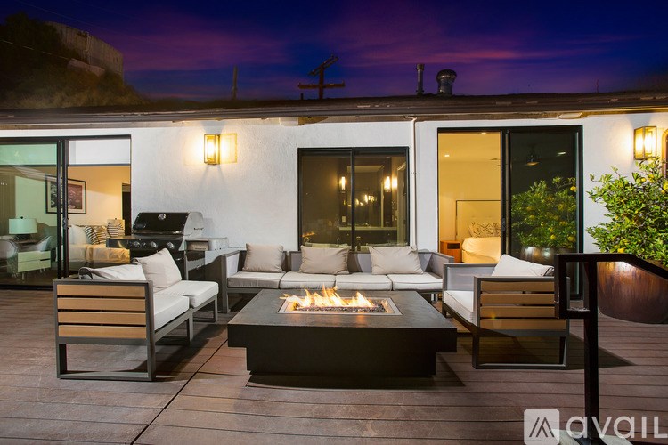 A modern outdoor patio with a fire pit and seating area.