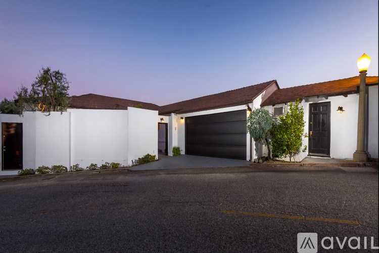 A house with a white exterior and a brown roof is shown with a driveway in front.