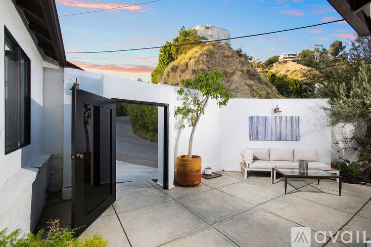 A patio with a white couch and a table with a plant in a pot.