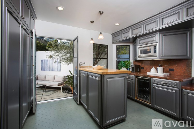 A modern kitchen with dark grey cabinets and a wooden island.