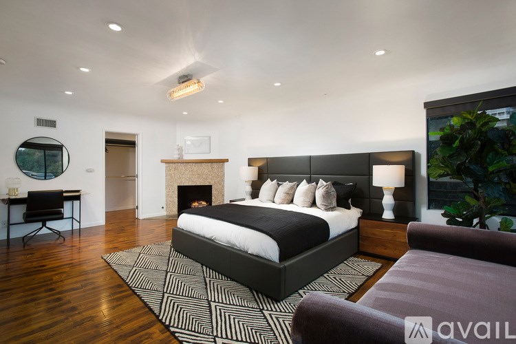 A modern bedroom with a large bed and a fireplace.