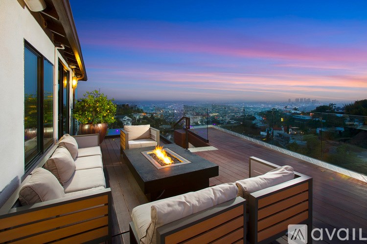 A patio with a table and chairs overlooking a cityscape at dusk.
