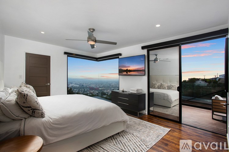 A bedroom with a large bed and a view of the city from the window.